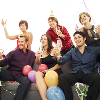 Group of Young People at a Party Sitting on a Couch with Champagne